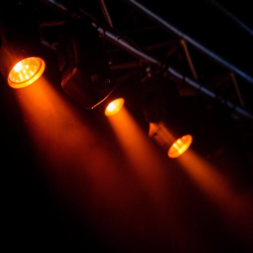 Luces de escenario naranjas reflejadas en superficies oscuras